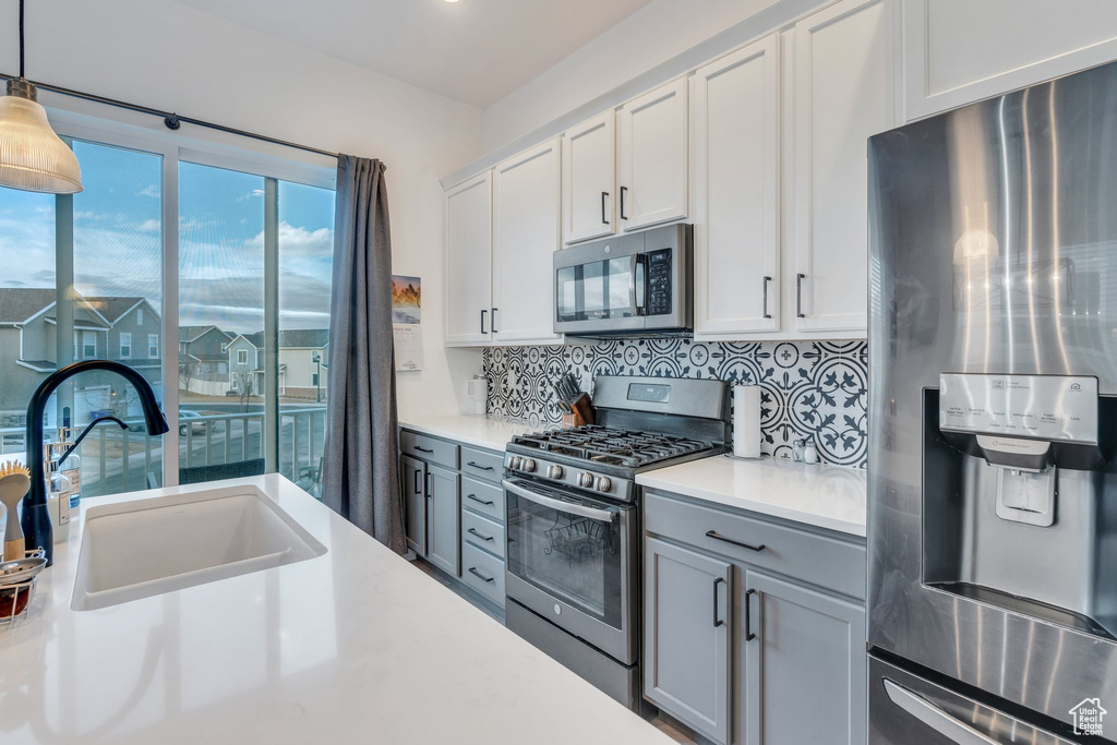 Kitchen featuring tasteful backsplash, hanging light fixtures, a sink, light countertops, and stainless steel appliances