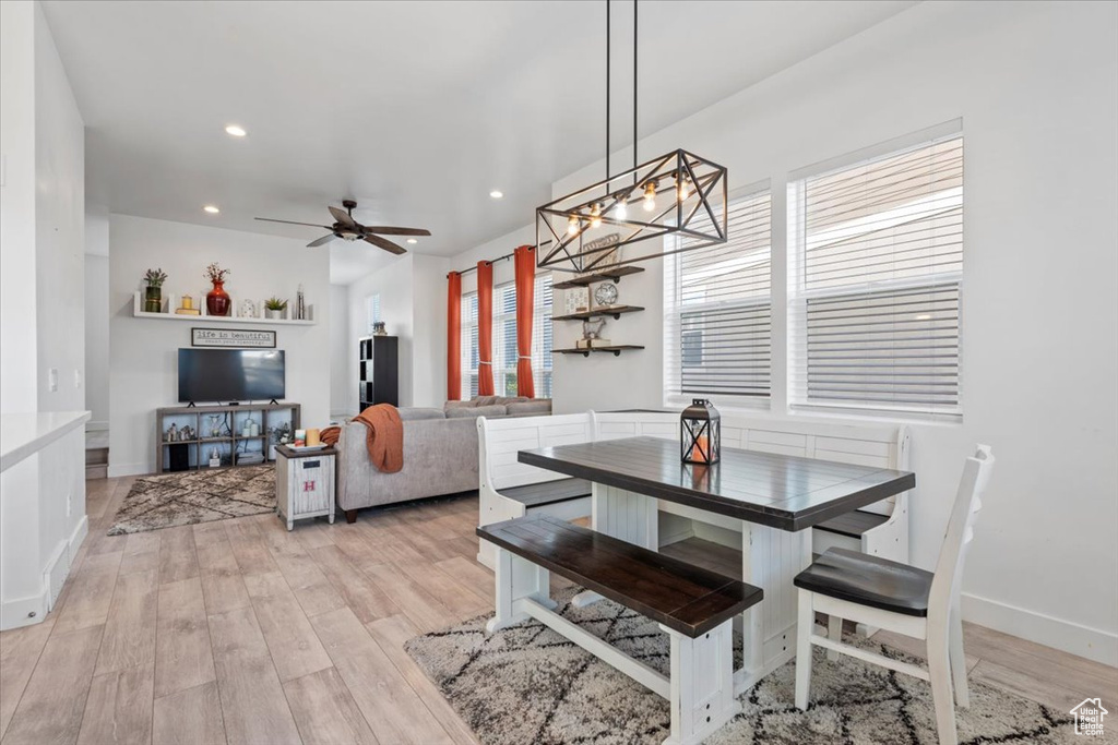 Dining area with light wood finished floors, a ceiling fan, a chandelier, and recessed lighting