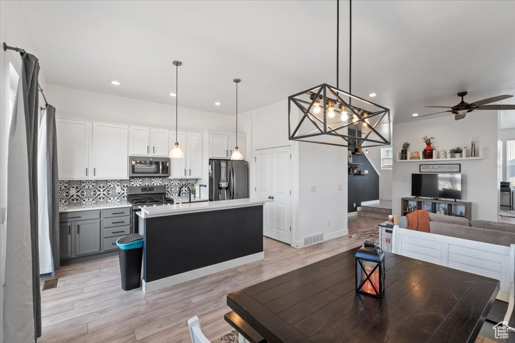 Living room with a ceiling fan, light wood-style flooring, a chandelier, and recessed lighting