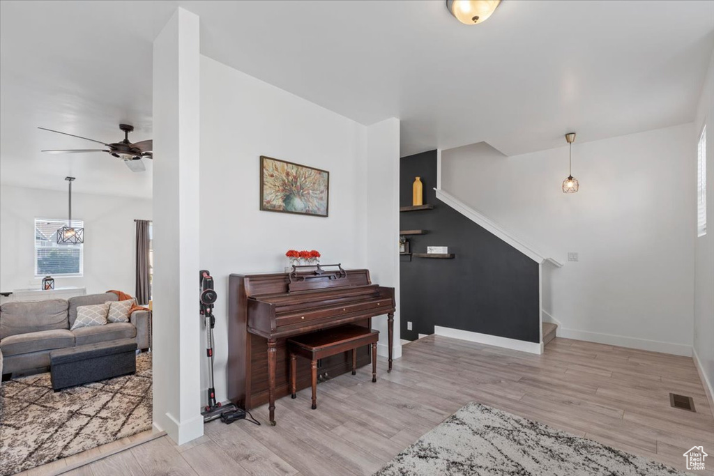 Sitting room with stairs, light wood-style floors, and ceiling fan