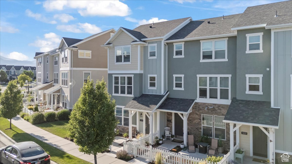 View of front of home with a residential view, stone siding, a porch, and stucco siding