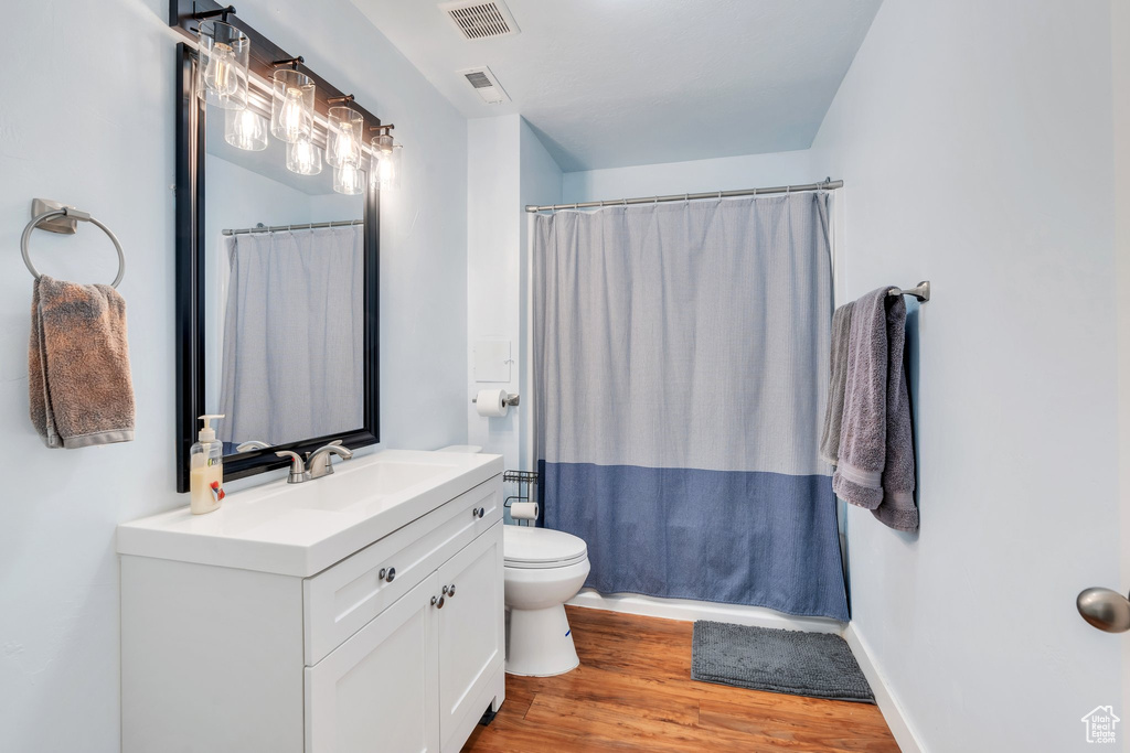 Full bathroom featuring vanity, toilet, wood finished floors, and visible vents