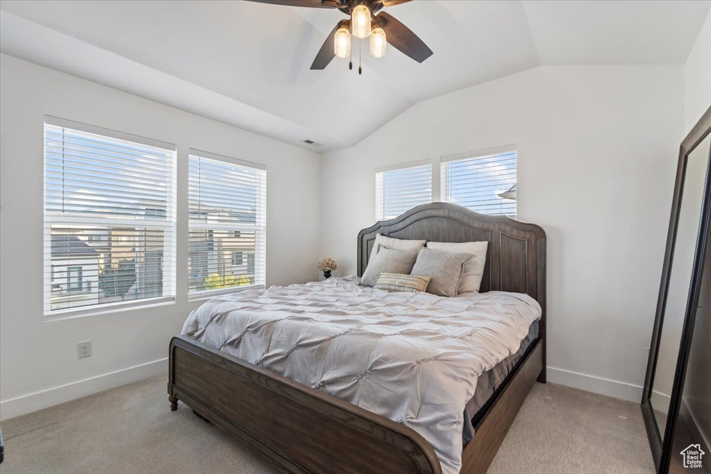 Bedroom with multiple windows, lofted ceiling, light colored carpet, and a ceiling fan