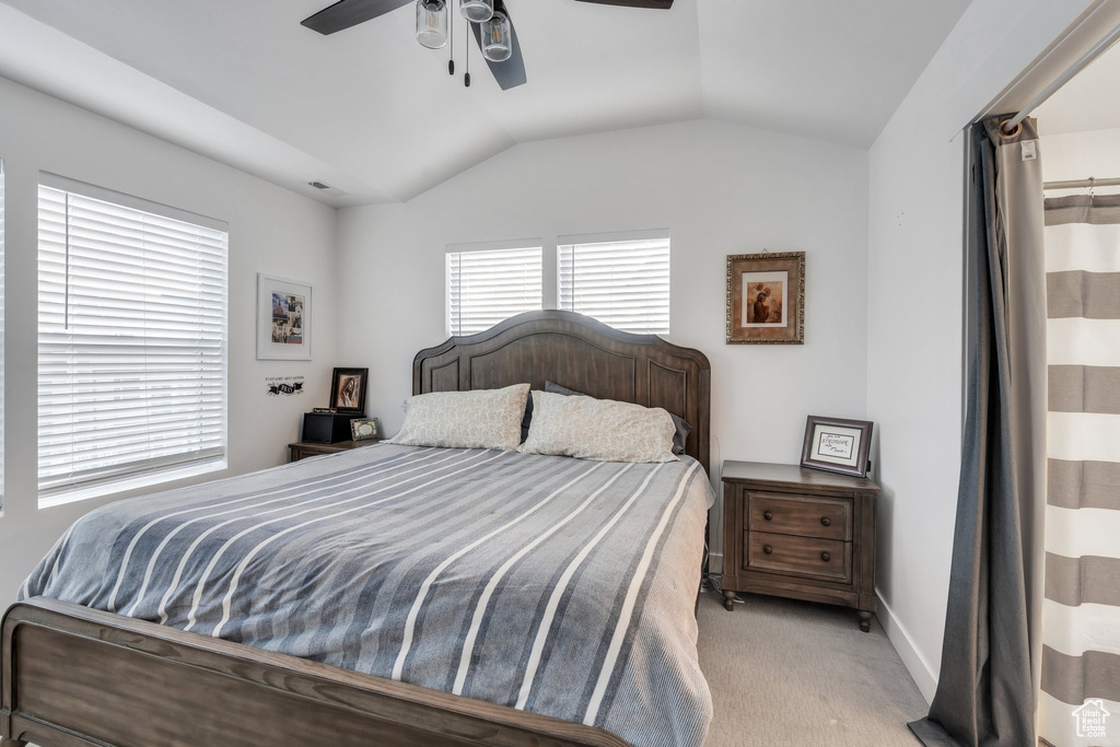 Bedroom featuring a ceiling fan, baseboards, vaulted ceiling, and light carpet