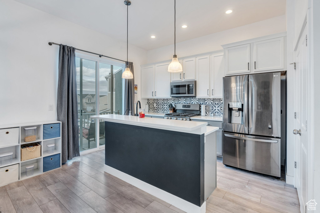 Kitchen featuring light wood-style floors, light countertops, backsplash, and stainless steel appliances