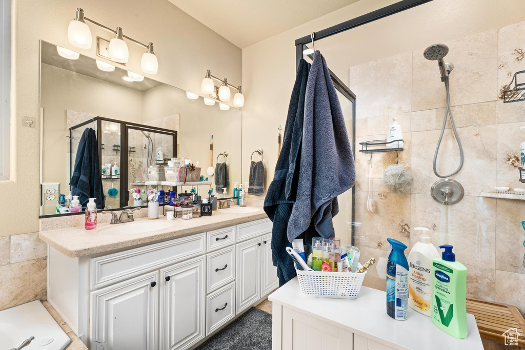 Bathroom with double vanity, a sink, and a stall shower
