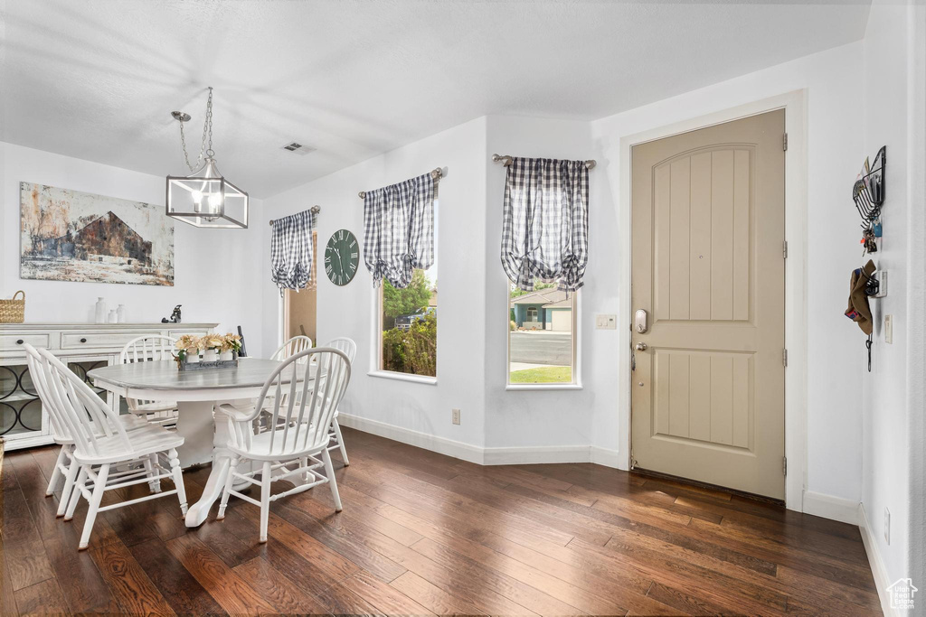 Dining area with an inviting chandelier, dark wood finished floors, baseboards, and a healthy amount of sunlight