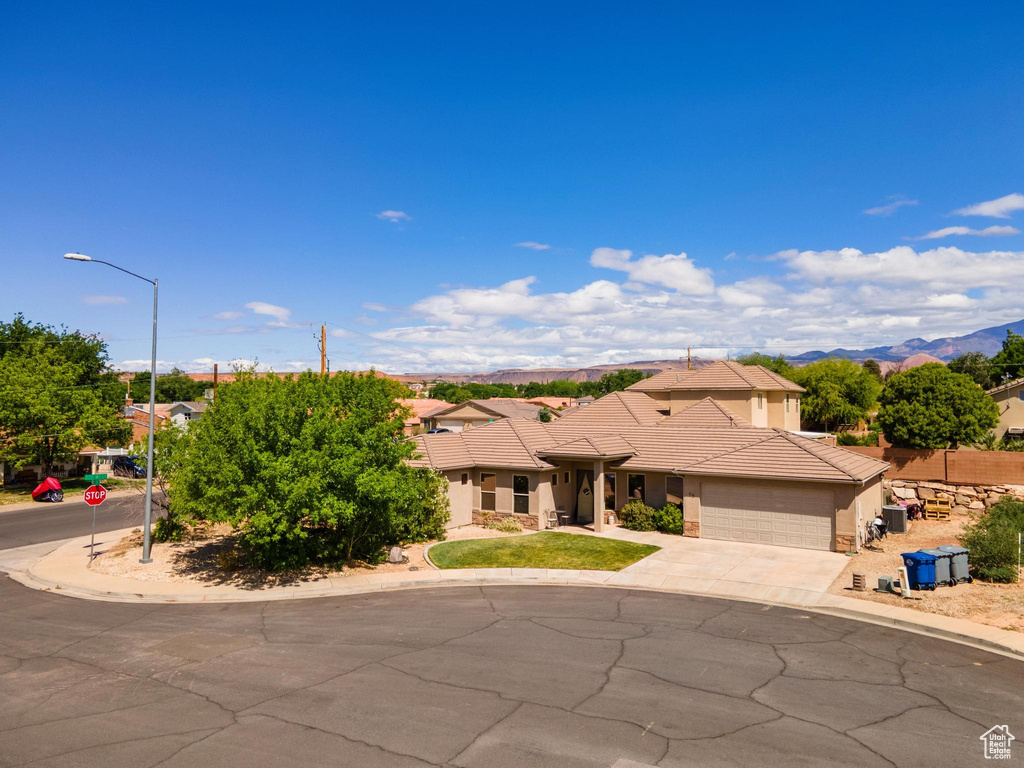 View of front of home with a tiled roof, driveway, a mountain view, an attached garage, and stucco siding