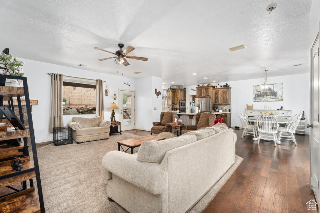 Living area featuring a ceiling fan, dark wood-style flooring, a textured ceiling, visible vents, and recessed lighting