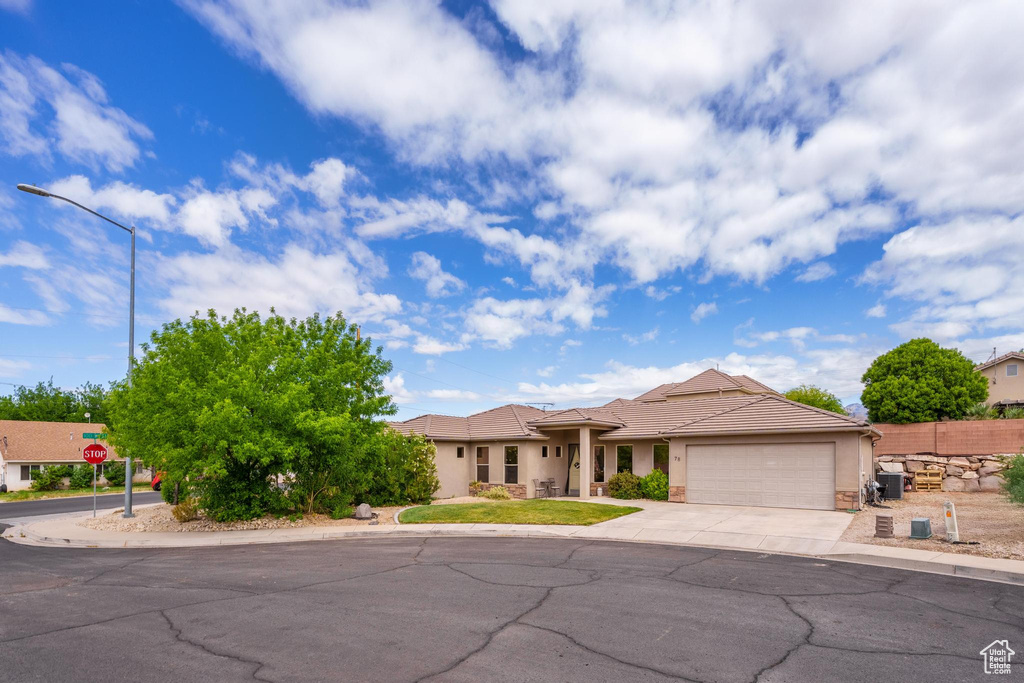 View of front facade with a garage, fence, stucco siding, a tiled roof, and concrete driveway