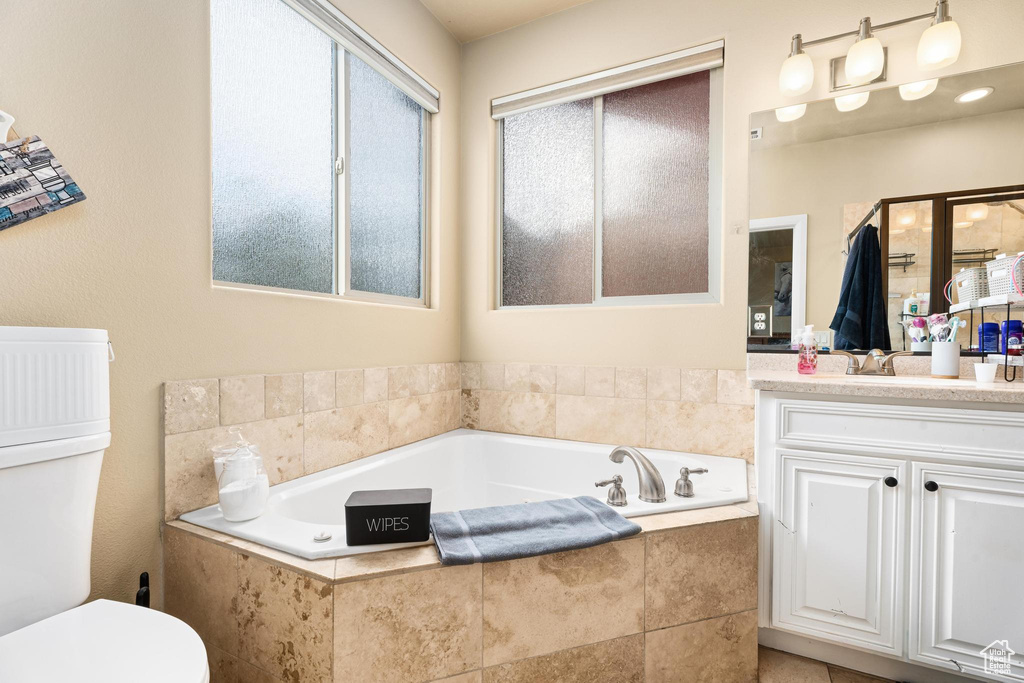 Bathroom featuring vanity, toilet, and a bath