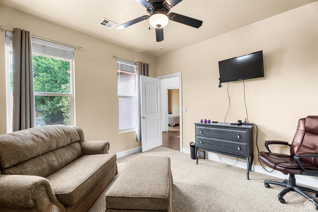 Living area with carpet flooring, a ceiling fan, baseboards, and visible vents