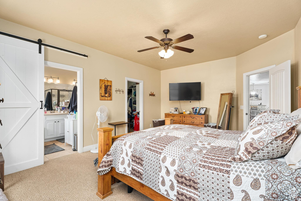 Bedroom featuring a closet, ceiling fan, light colored carpet, a barn door, and a spacious closet