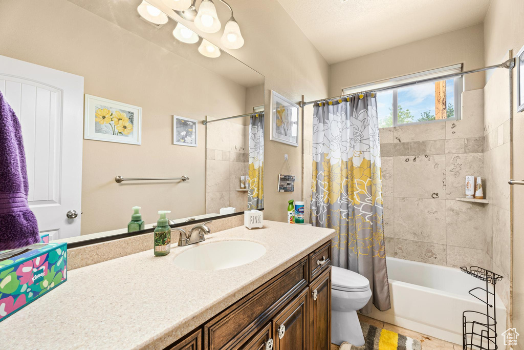 Bathroom featuring vanity, shower / bath combination with curtain, and toilet