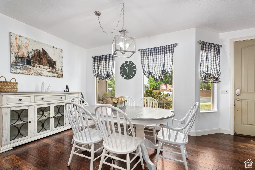Dining area featuring baseboards, dark wood-style flooring, and a chandelier