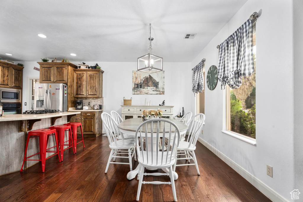 Dining room with baseboards, dark wood-type flooring, recessed lighting, and visible vents