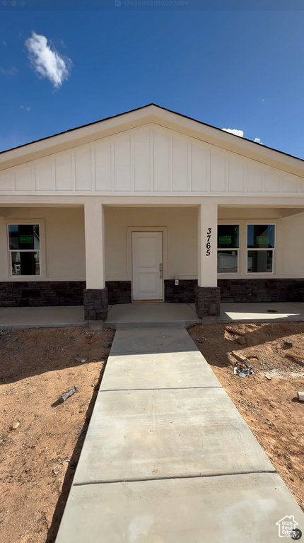 View of front of property with a porch, board and batten siding, and stone siding