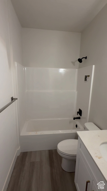 Full bath featuring toilet, washtub / shower combination, wood finished floors, and vanity
