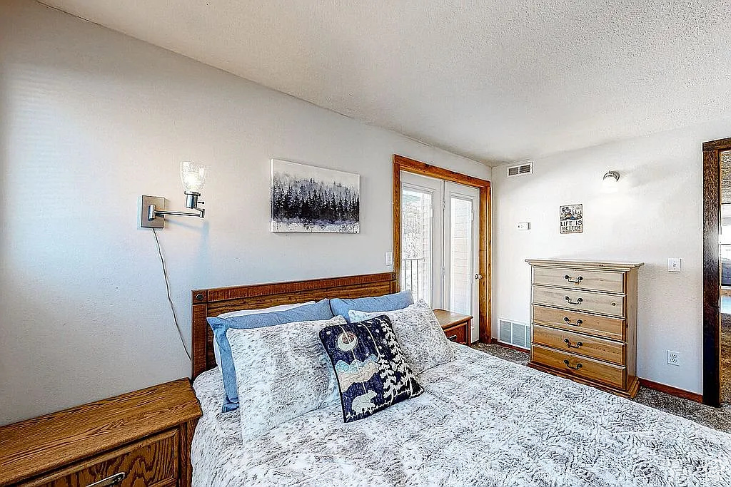 Carpeted bedroom with a textured ceiling, visible vents, baseboards, and access to outside
