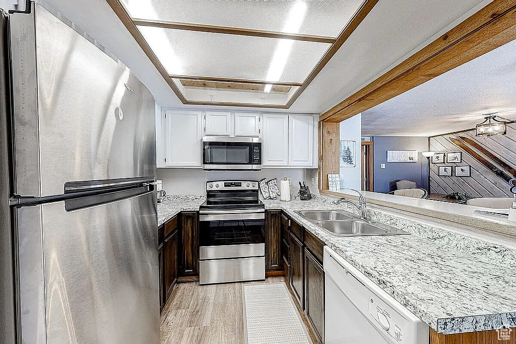 Kitchen with light countertops, appliances with stainless steel finishes, white cabinetry, and a sink