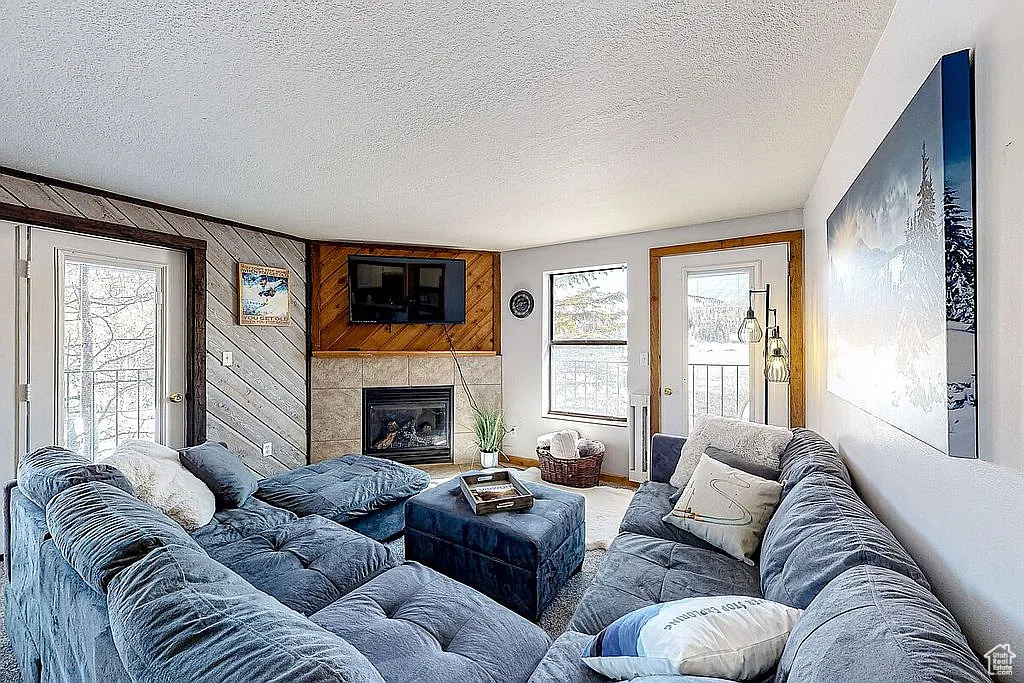 Living area featuring a tiled fireplace, a textured ceiling, and a healthy amount of sunlight