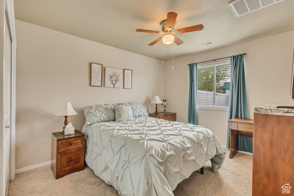 Bedroom with baseboards, visible vents, light carpet, and ceiling fan
