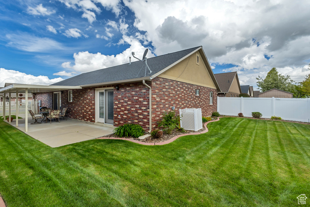 Rear view of house with brick siding, cooling unit, a fenced backyard, a yard, and a patio