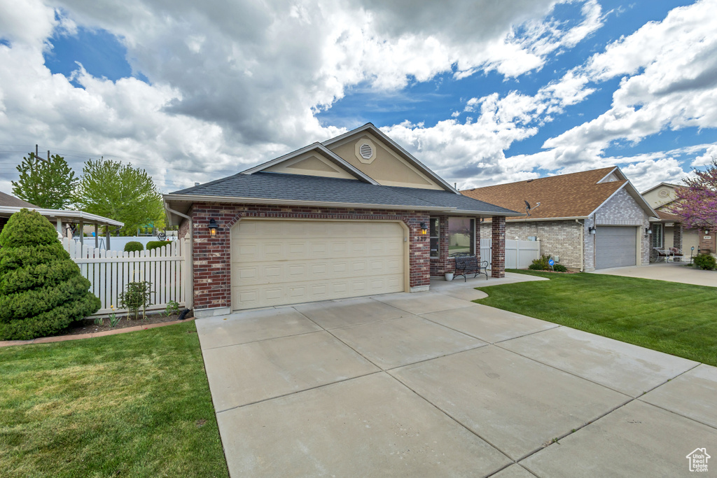 Single story home featuring brick siding, fence, and a front lawn
