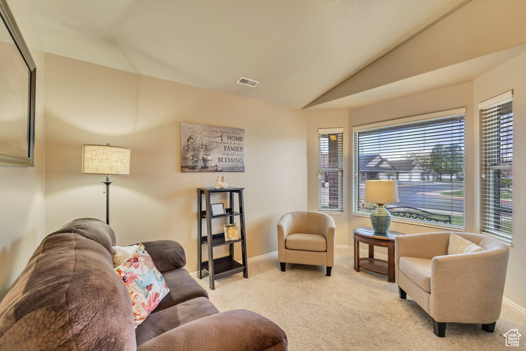 Living room with baseboards, light carpet, vaulted ceiling, and visible vents