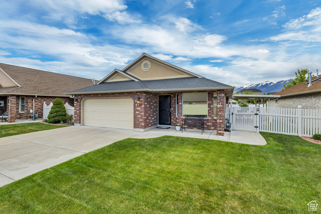 Ranch-style home featuring fence, an attached garage, concrete driveway, and a front yard