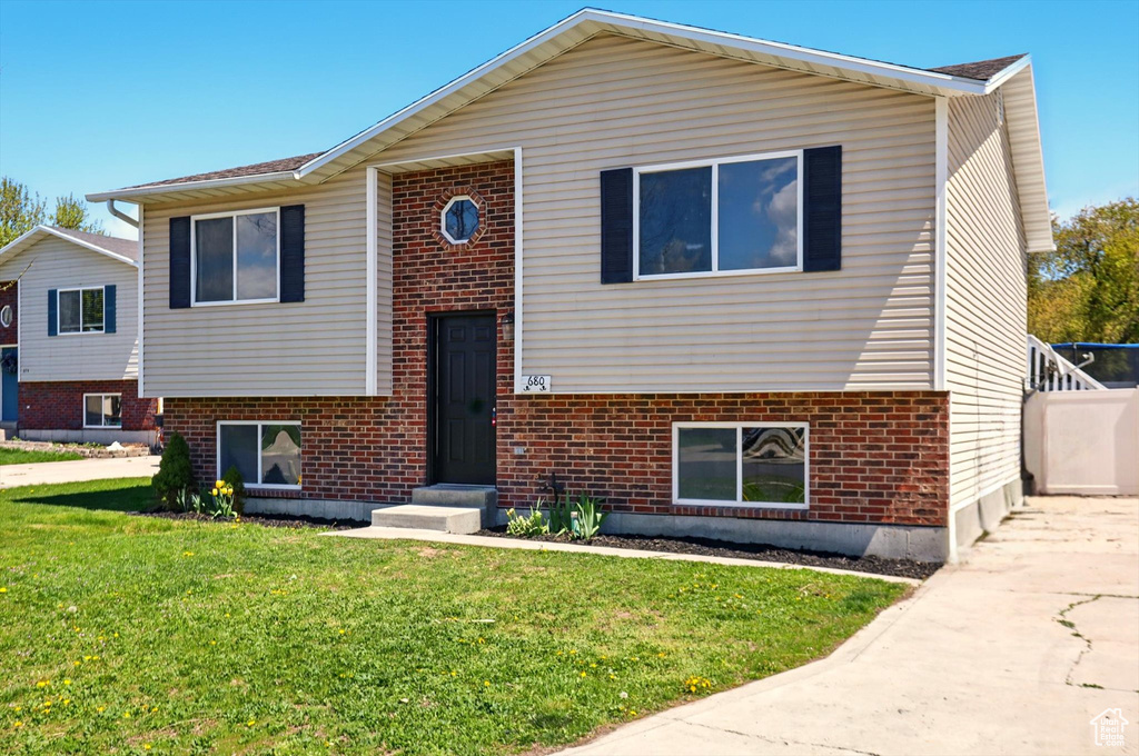 Bi-level home featuring brick siding, a front lawn, and driveway