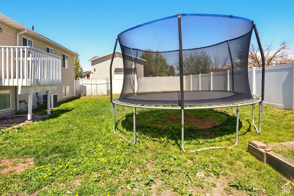 View of yard with a fenced backyard, a trampoline, and central air condition unit