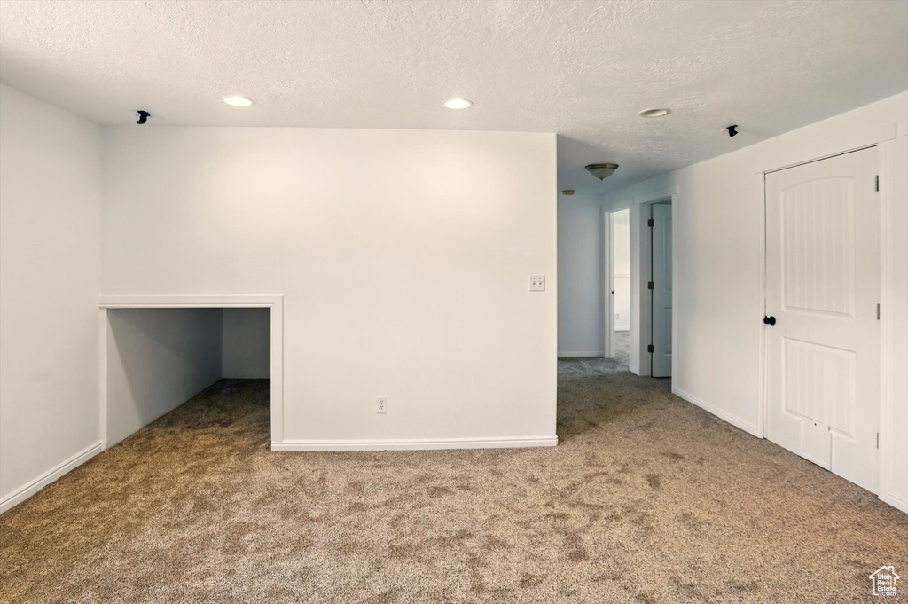 Carpeted empty room with recessed lighting, a textured ceiling, and baseboards