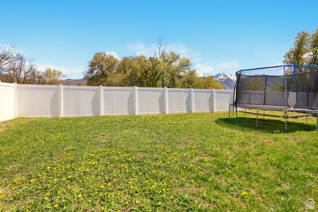 View of yard featuring a fenced backyard and a trampoline