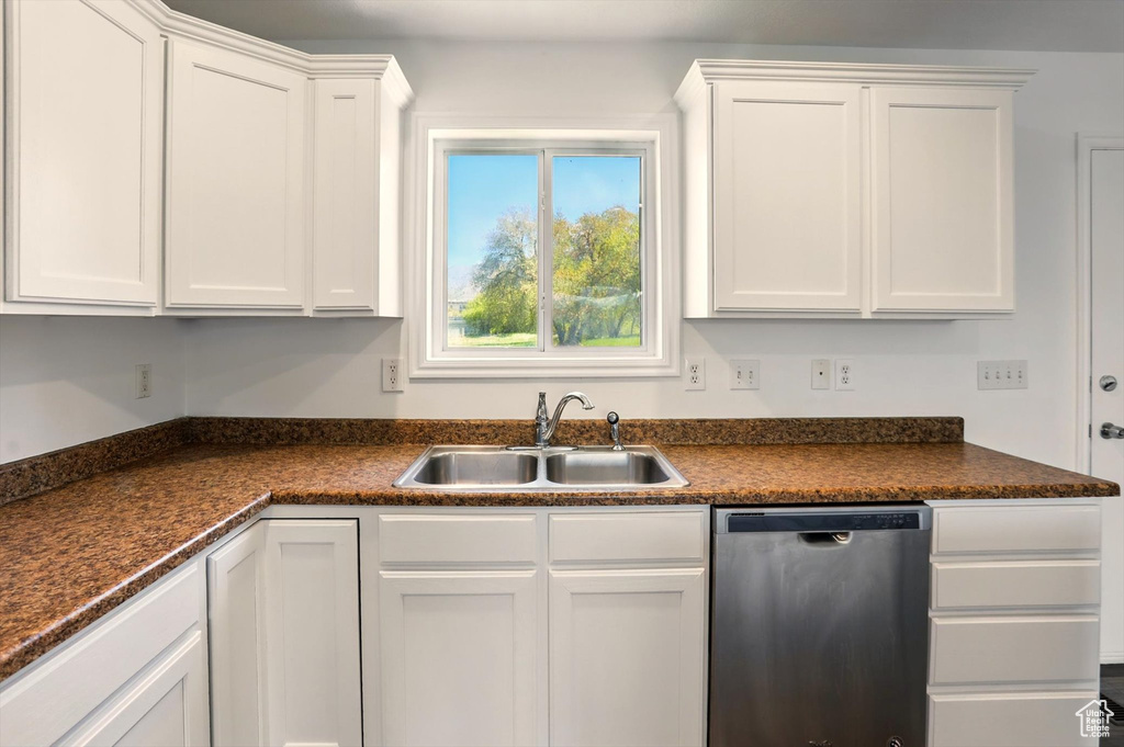 Kitchen featuring a sink, dark countertops, white cabinetry, and dishwasher