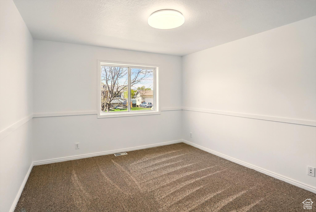 Carpeted spare room with visible vents and baseboards