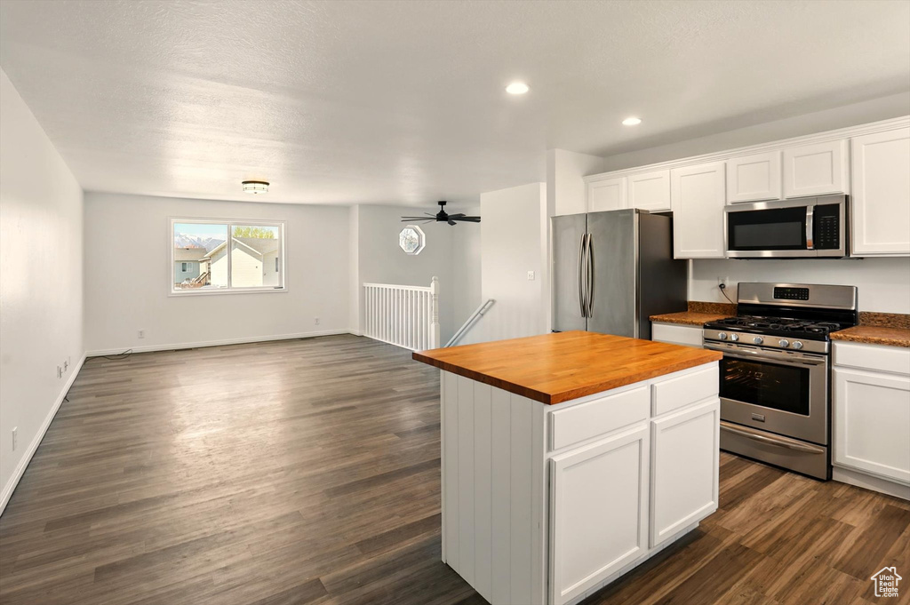 Kitchen with white cabinetry, appliances with stainless steel finishes, butcher block counters, and dark wood finished floors