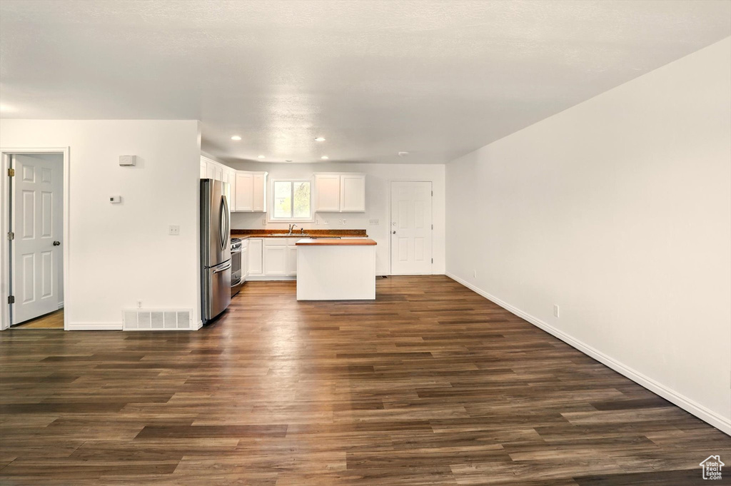 Unfurnished living room with visible vents, dark wood-style flooring, and baseboards