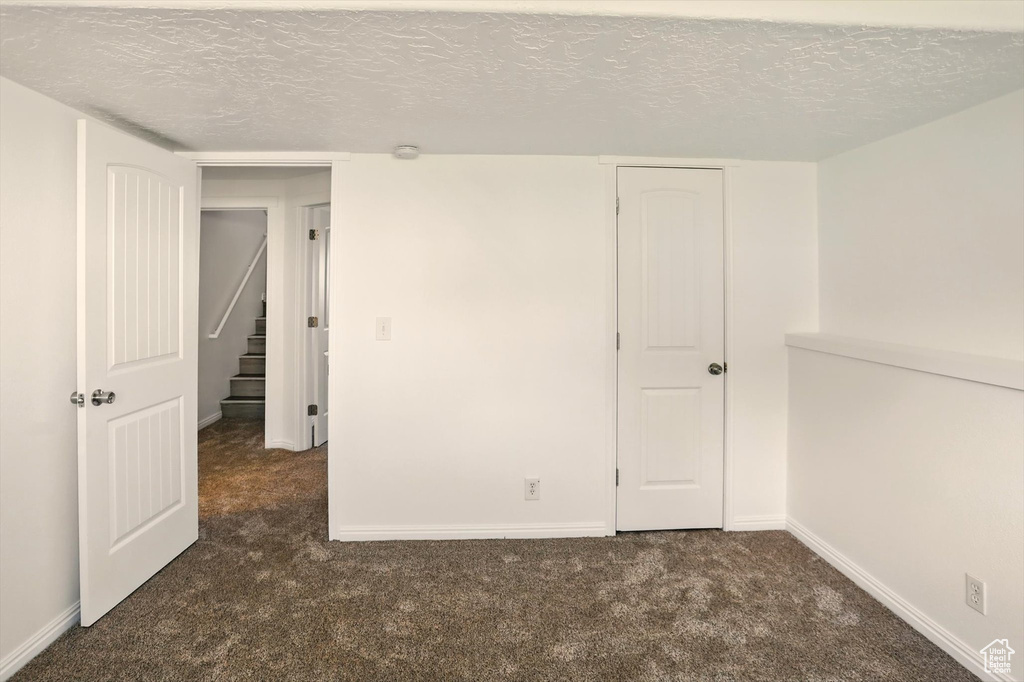 Spare room featuring baseboards, a textured ceiling, and carpet