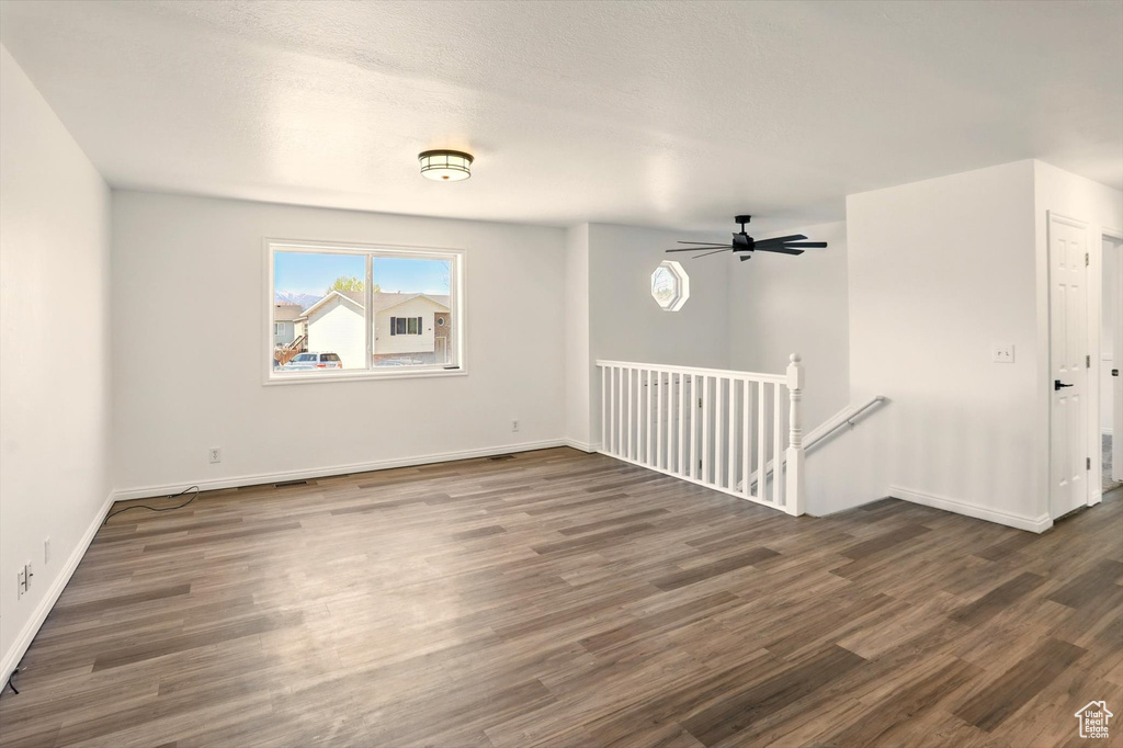 Spare room featuring baseboards, ceiling fan, and dark wood-style floors