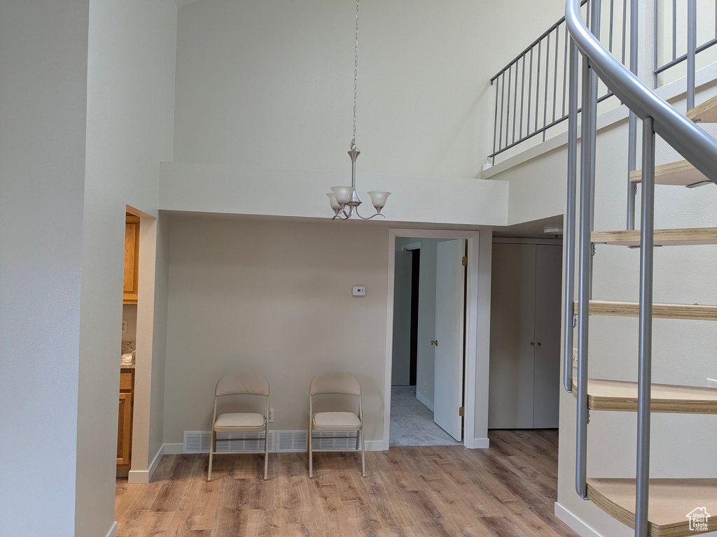 Interior space with visible vents, a towering ceiling, wood finished floors, and a chandelier