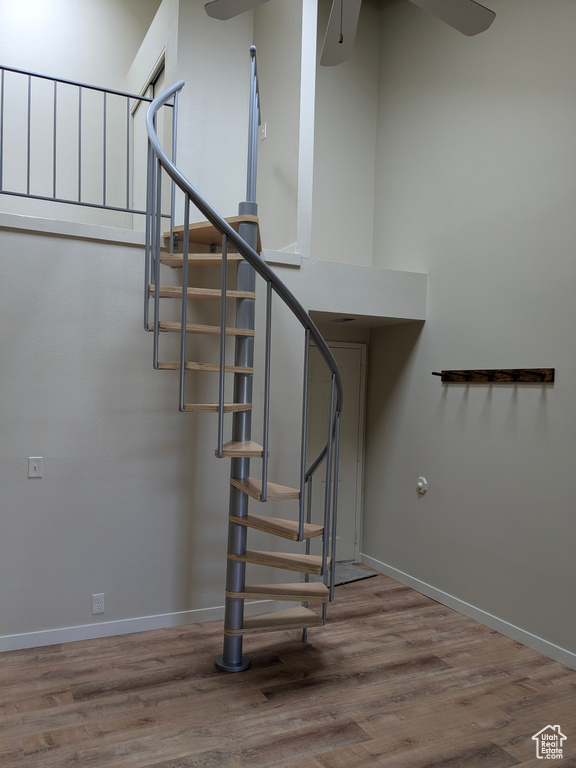 Stairs featuring a ceiling fan, baseboards, and wood finished floors