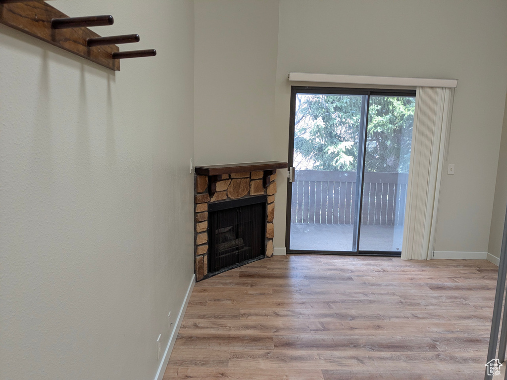 Unfurnished living room featuring baseboards, wood finished floors, and a fireplace