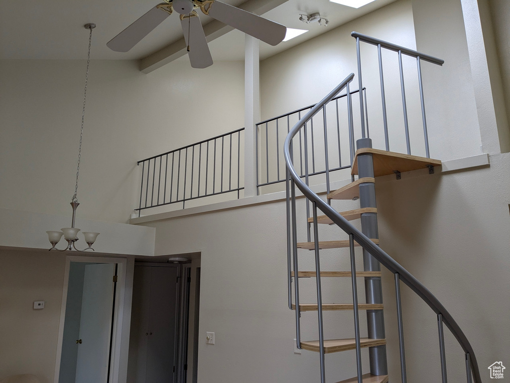 Stairs featuring a ceiling fan, beam ceiling, and high vaulted ceiling