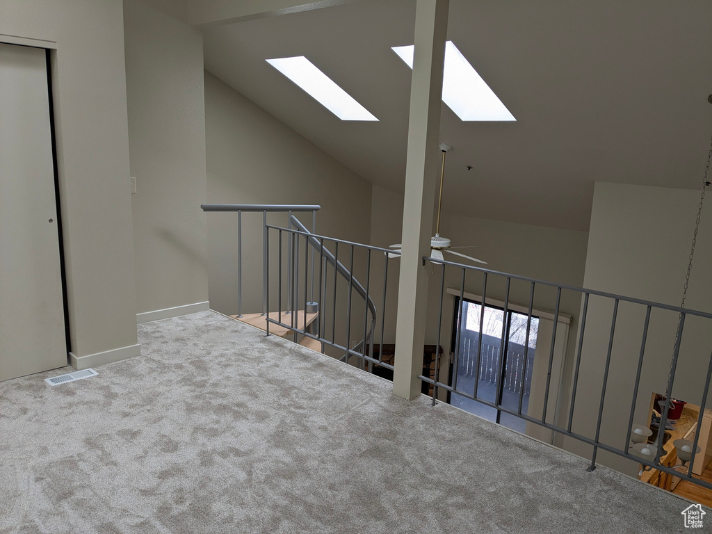 Interior space with carpet floors, visible vents, high vaulted ceiling, a ceiling fan, and a skylight