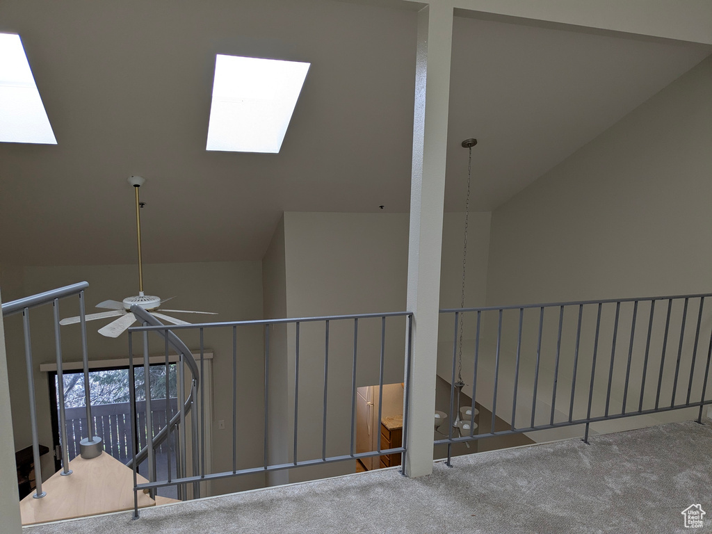 Stairway with carpet, lofted ceiling with skylight, and ceiling fan