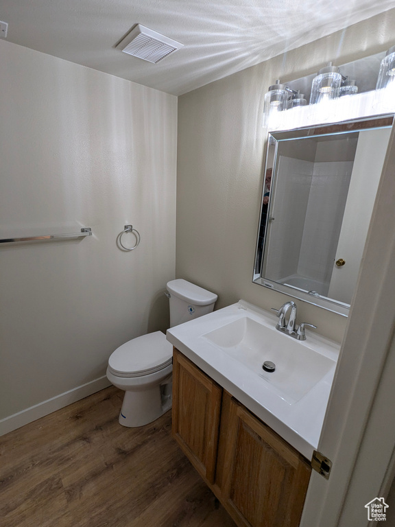 Bathroom featuring toilet, visible vents, wood finished floors, and vanity