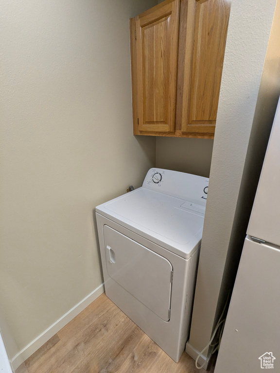 Washroom featuring baseboards, light wood-style flooring, washer / dryer, and cabinet space