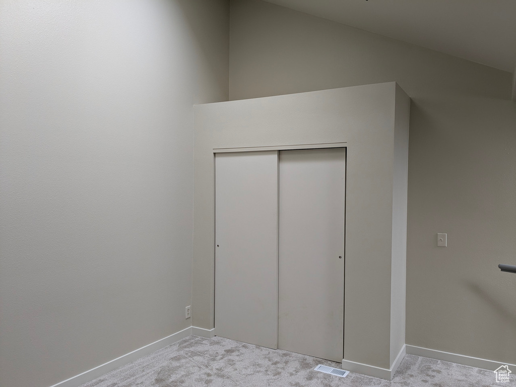 Unfurnished bedroom with baseboards, light colored carpet, visible vents, and a closet