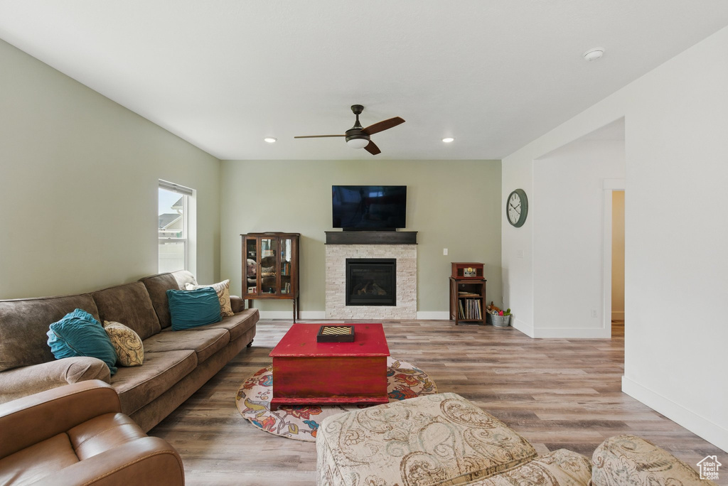 Living room featuring a glass covered fireplace, wood finished floors, baseboards, ceiling fan, and recessed lighting